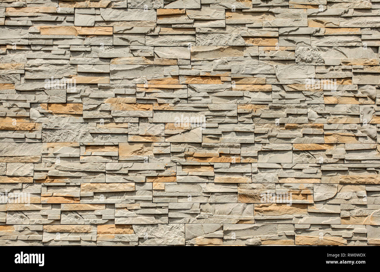 Tiled stone wall made of rectangular blocks, sun shining from top. Stock Photo