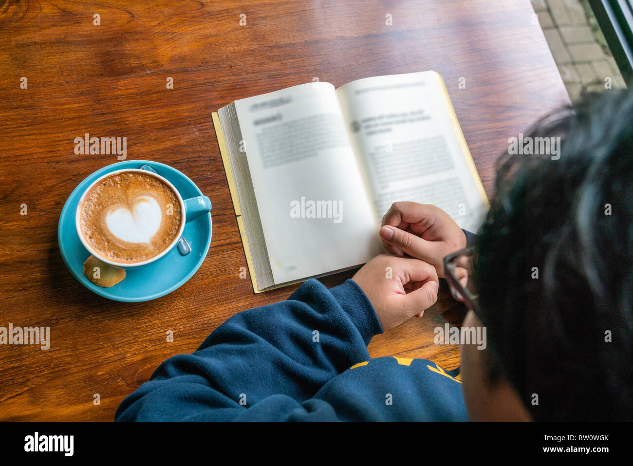 Top view of young girl reading book and drinking coffee Stock Photo