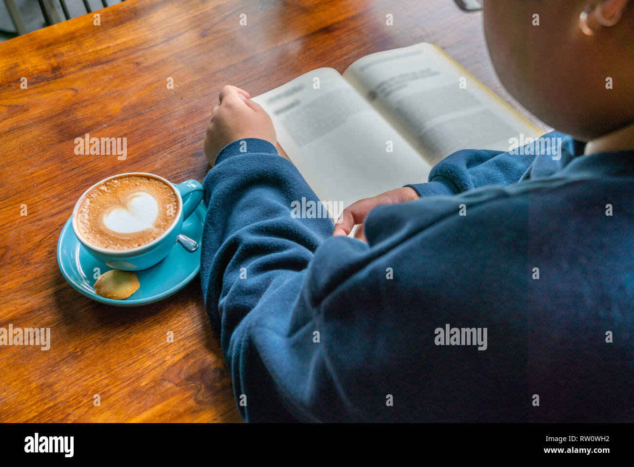 Young woman reading a book and drinking a cup of coffee Stock Photo