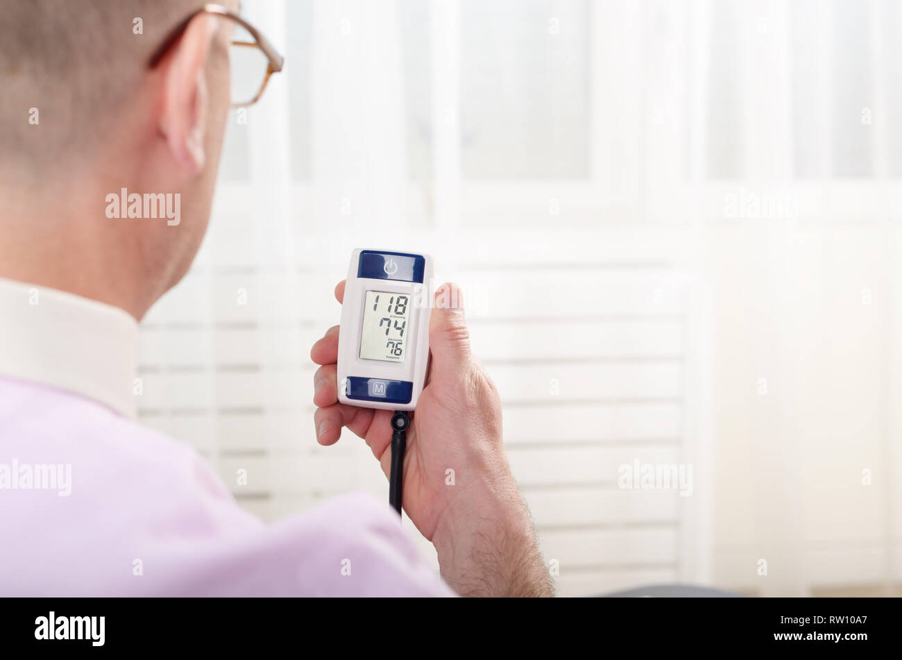 Man read measurement results from personal digital blood pressure monitor Stock Photo