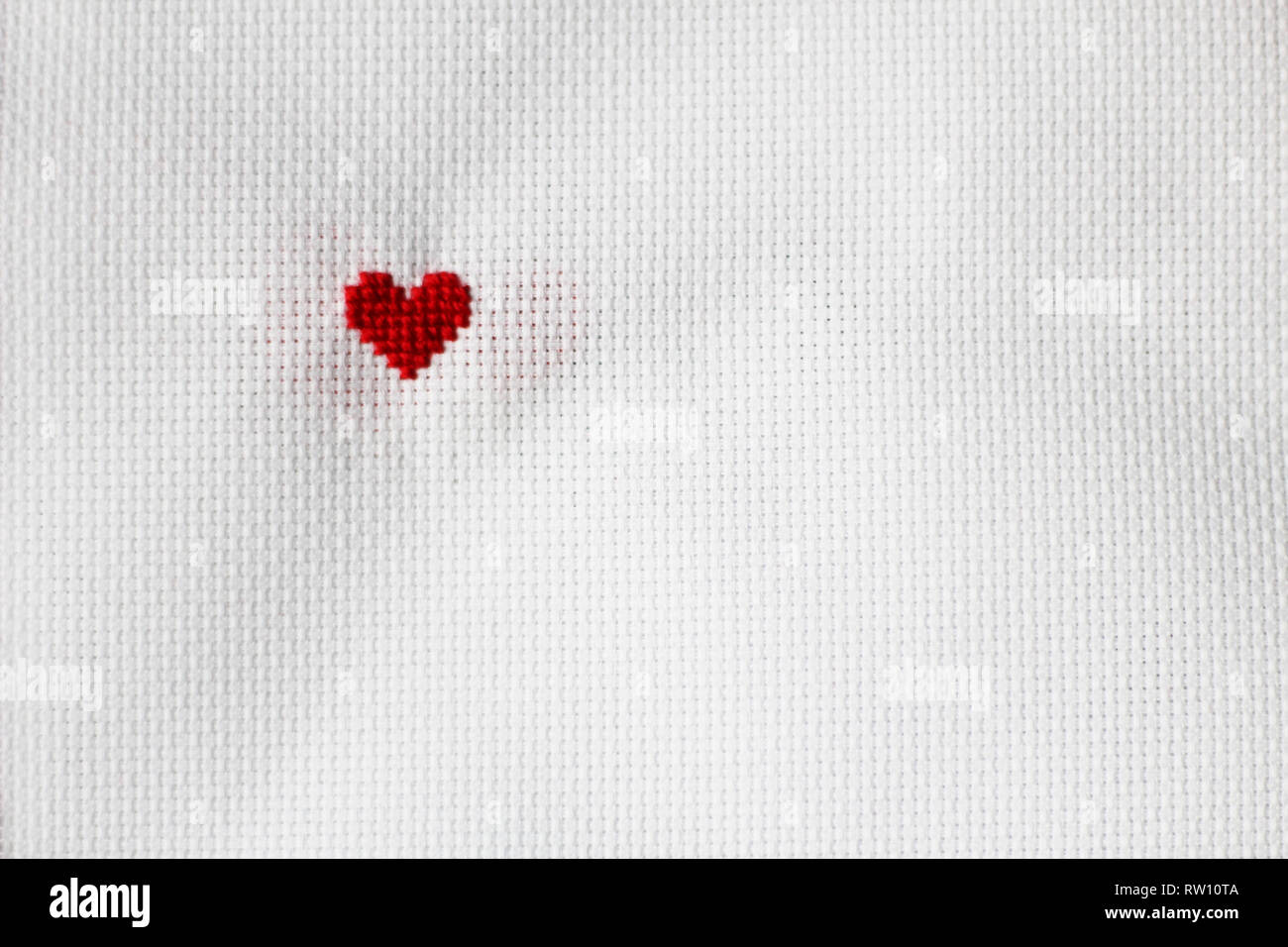 Cross stitched red heart, white background. free copy space Stock Photo