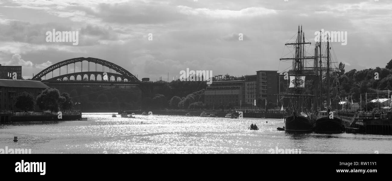 Monochrome image of Tall Ships at Port of Sunderland in North East England with Wearmouth bridge to the left and sailing ships to the right Stock Photo