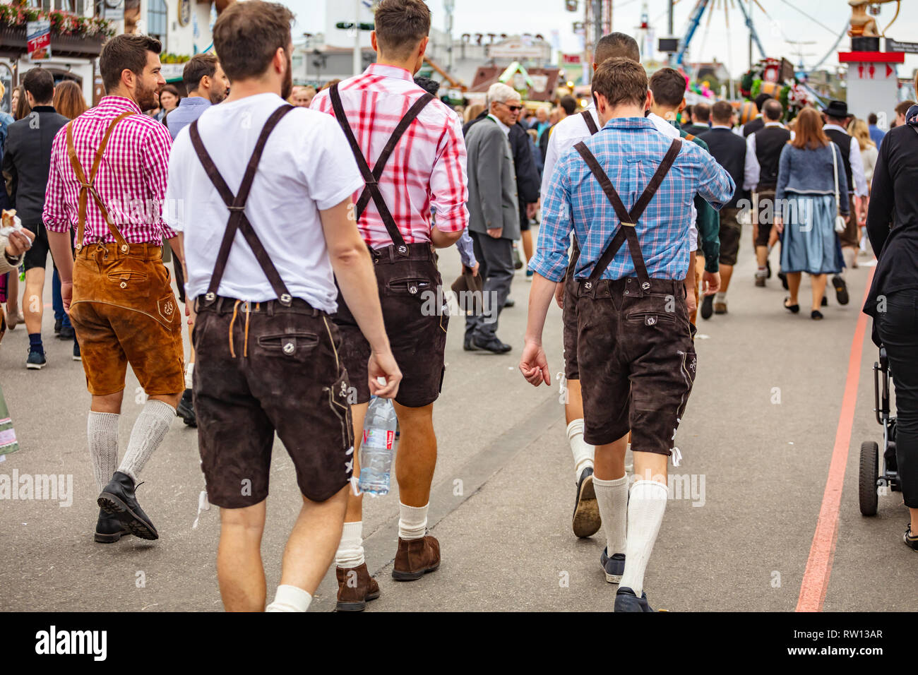 October 7, 2018. Munich, Germany, Oktoberfest, Group of young men in traditional costumes walking among the crowd, back view Stock Photo