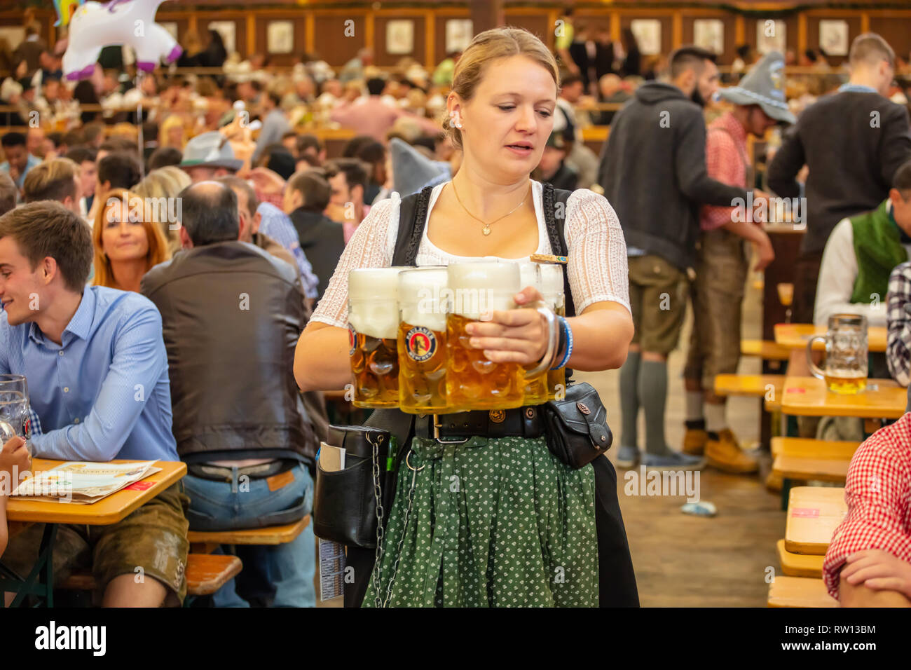 October 7, 2018. Munich, Germany, Oktoberfest, waitress in tyrolean costume  holding beers, tent interior background Stock Photo - Alamy