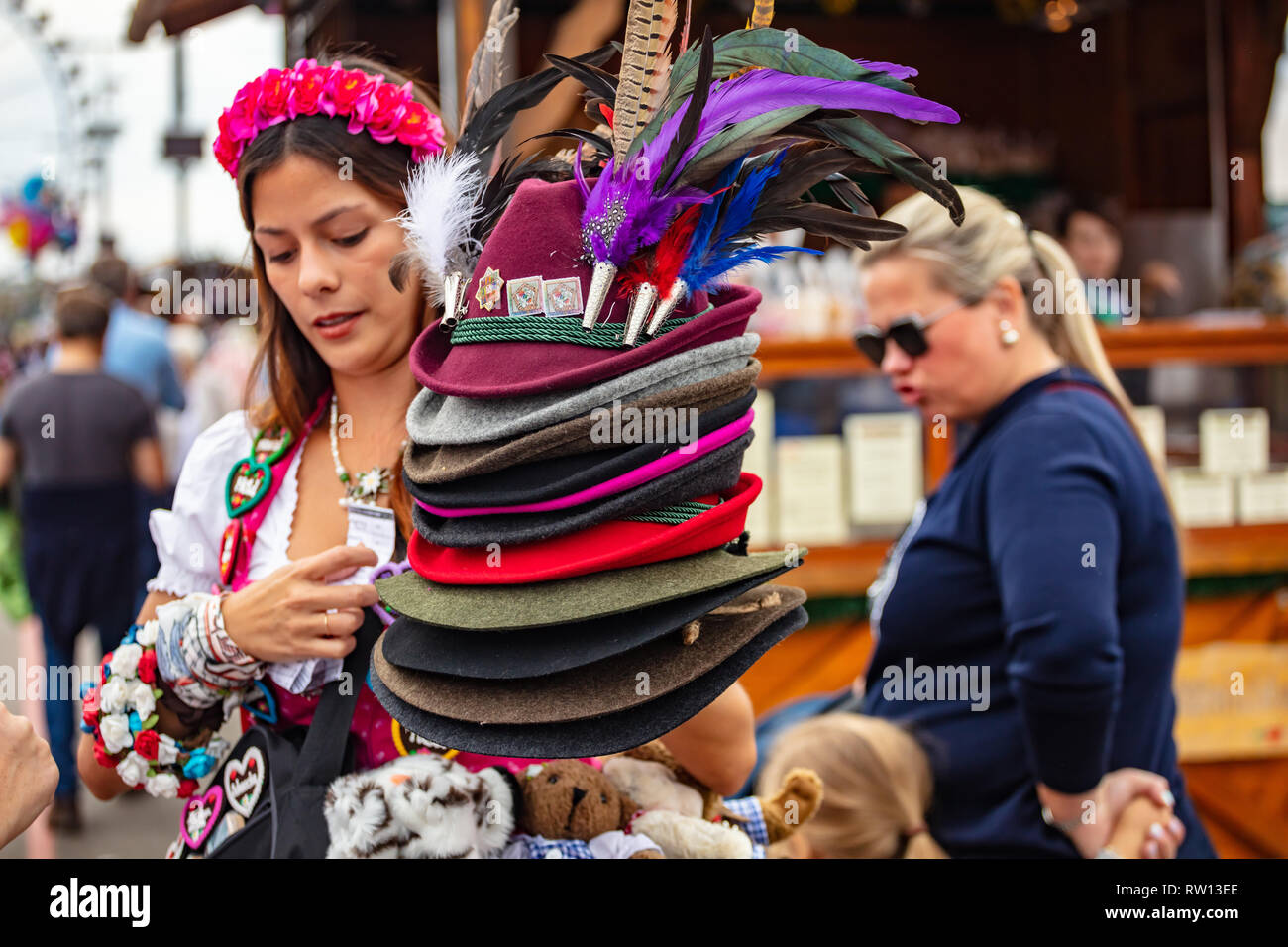 October 7, 2018. Munich, Germany, Oktoberfest, Young beautiful woman in traditional costume holding a stack of tyrolean alpine hats Stock Photo