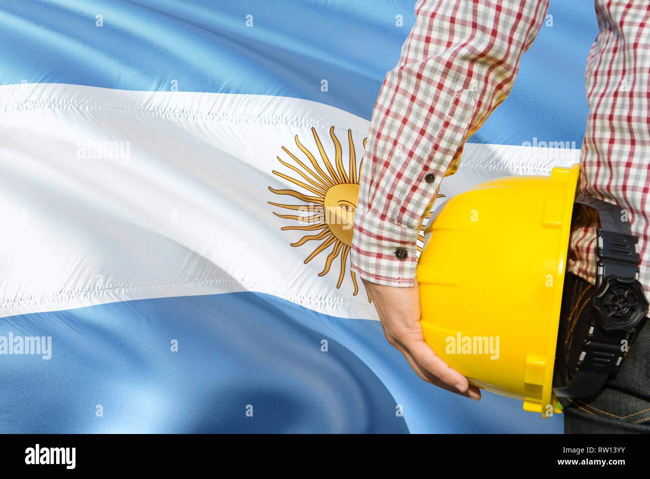 Argentine Engineer is holding yellow safety helmet with waving