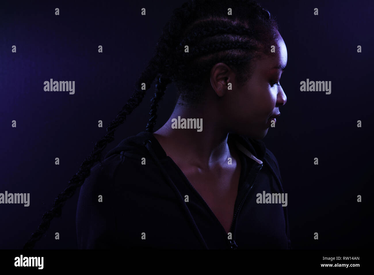 Cool and Beautiful Black Female Model Looking Away In Purple Light Stock Photo
