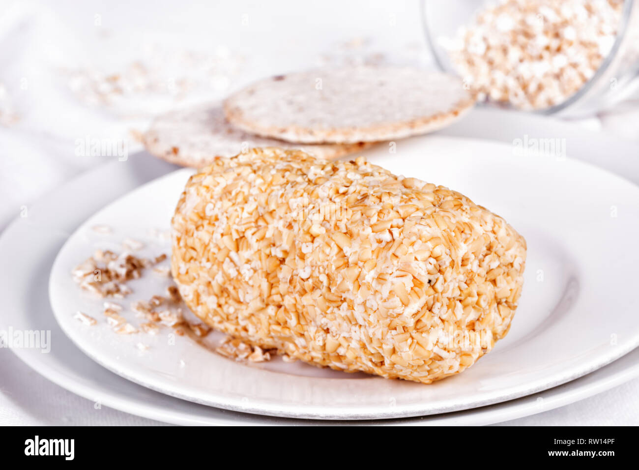 Scottish Highland cheese Caboc hand rolled in pinhead oatmeal on a plate, two oatcakes on side Stock Photo