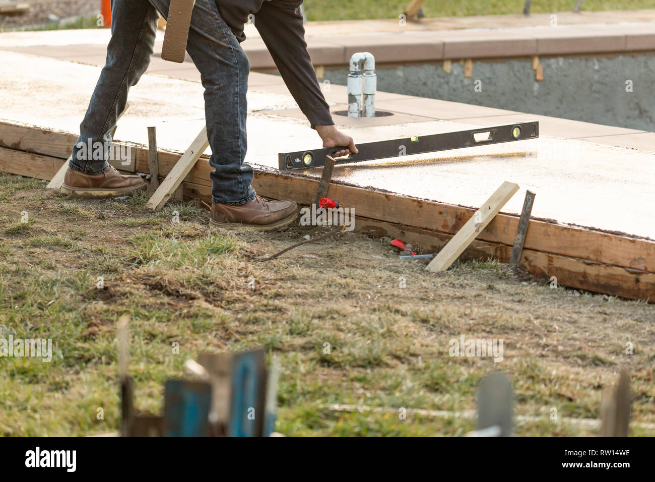 Construction Worker Checking Level On Wet Deck Cement Stock Photo