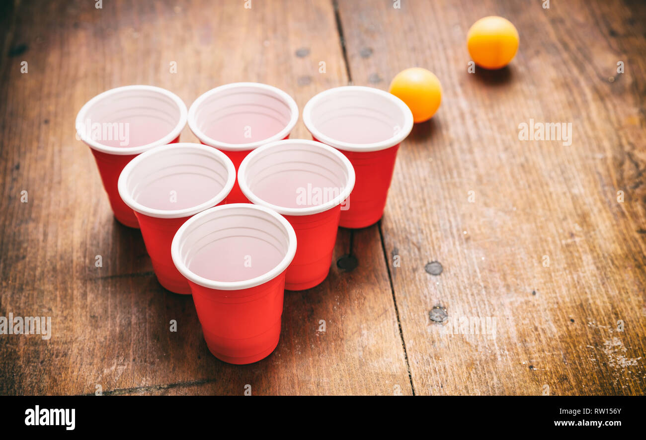 Beer pong, college party game. Plastic red color cups and ping pong balls  on wooden background, copy space Stock Photo - Alamy