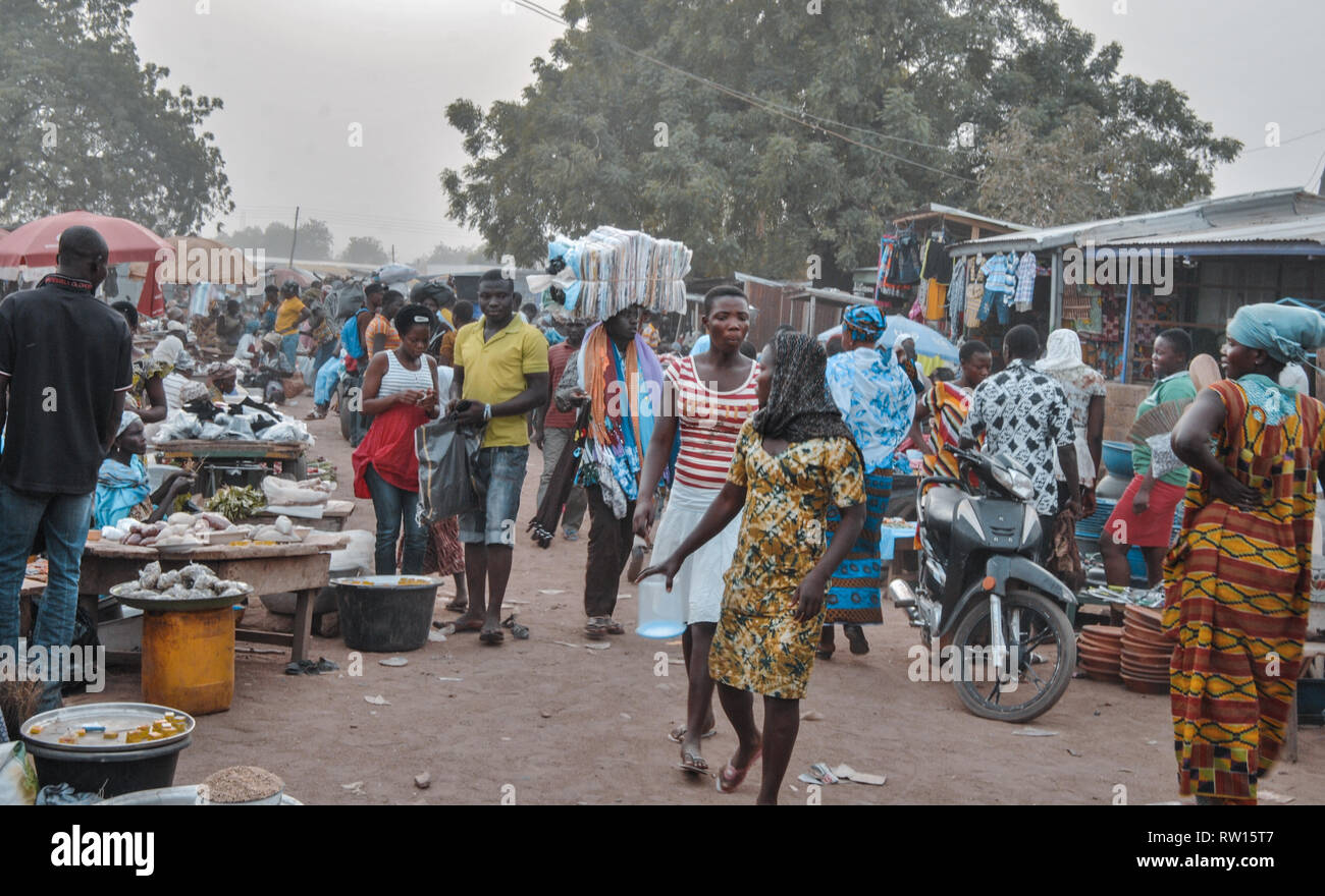 A photo of a busy farmer's market in Bolgatanga (Bolga), Ghana. People wearing traditional clothes and vendors can be seen. Stock Photo