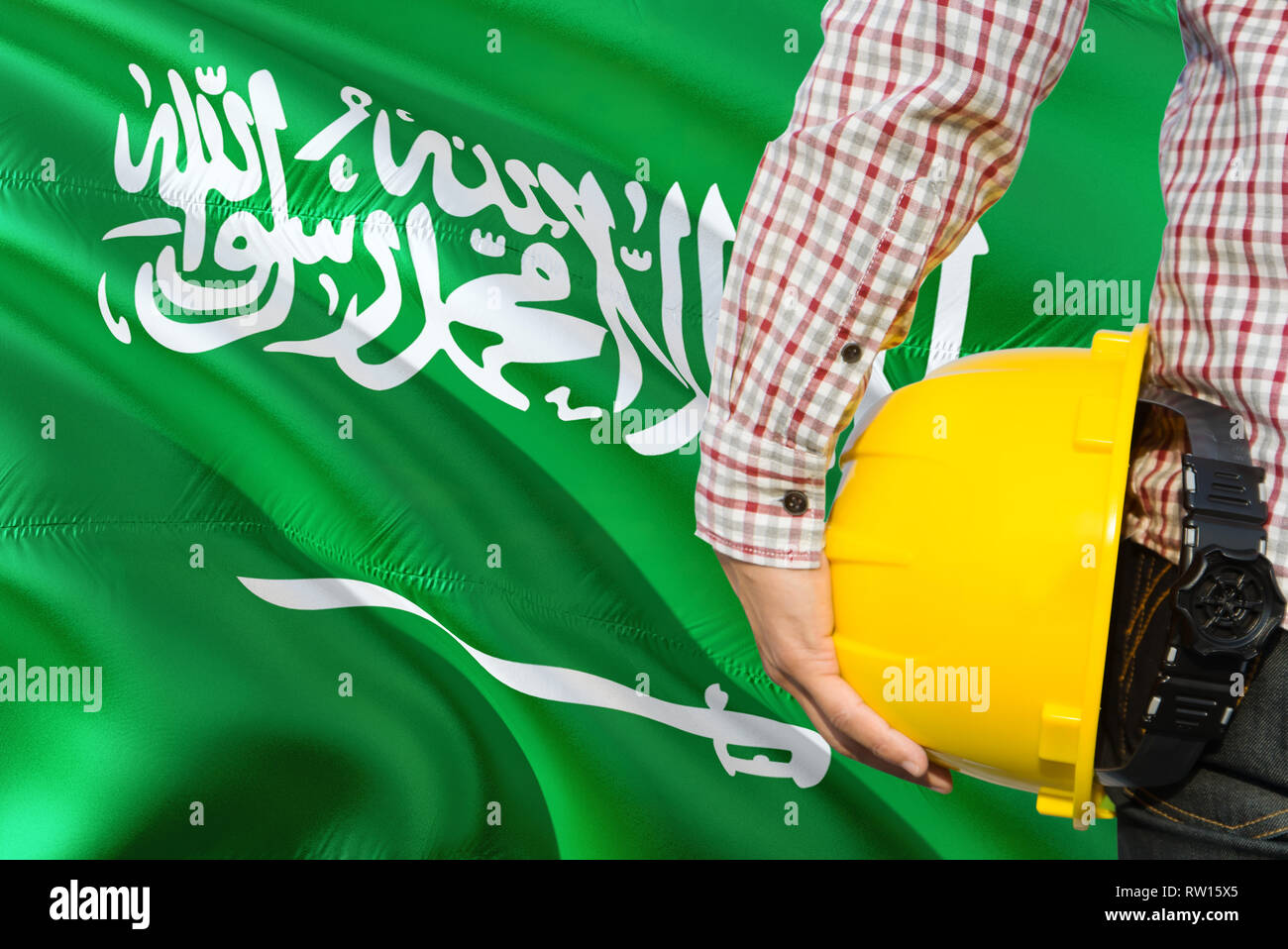 Saudi Engineer is holding yellow safety helmet with waving Saudi Arabia