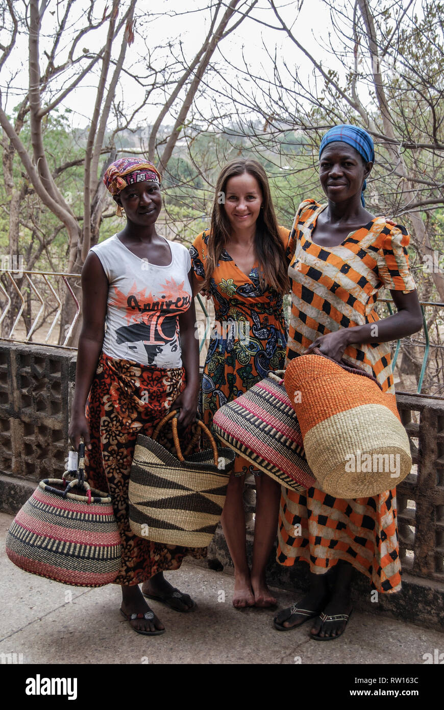 A nice photo of three happy and smiling women wearing traditional Ghanaian clothes posing for the camera with beautiful handwoven Bolga baskets Stock Photo