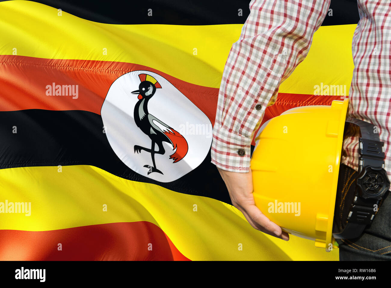 Ugandan Engineer is holding yellow safety helmet with waving Uganda