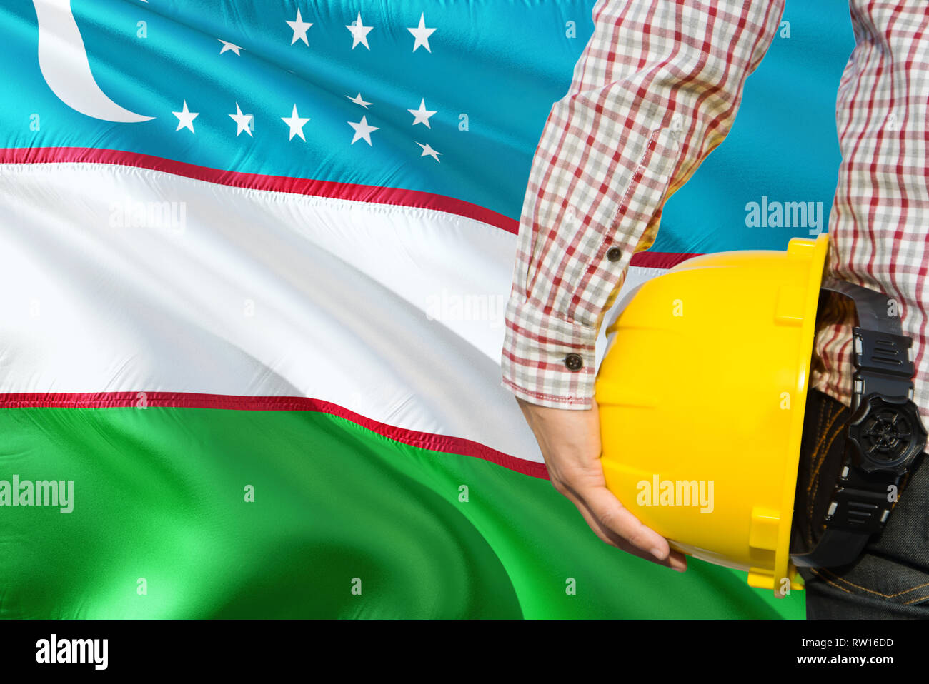 Uzbek Engineer is holding yellow safety helmet with waving Uzbekistan