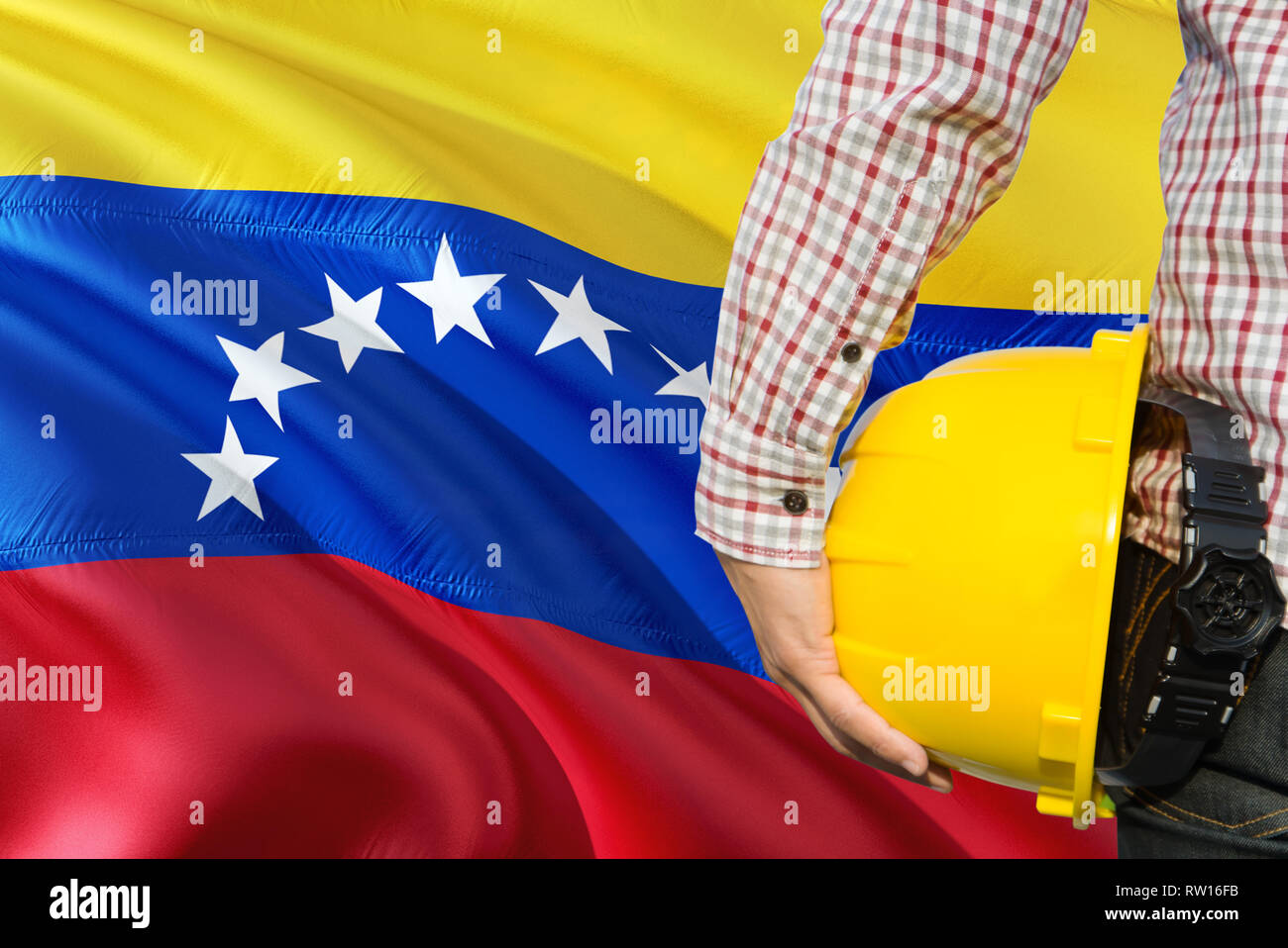 Venezuelan Engineer is holding yellow safety helmet with waving