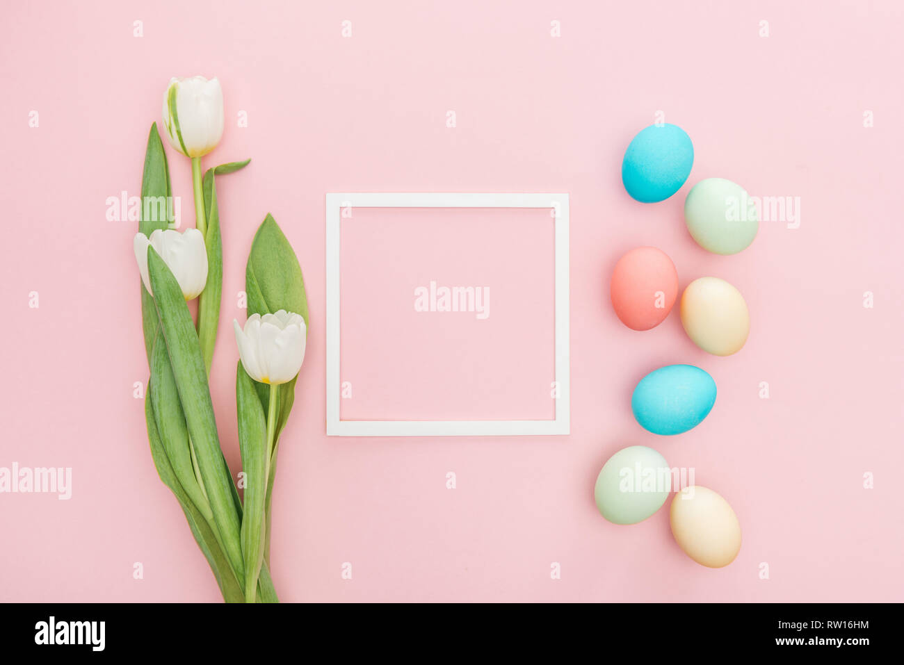 top view of tulip flowers and easter eggs with frame isolated on pink ...