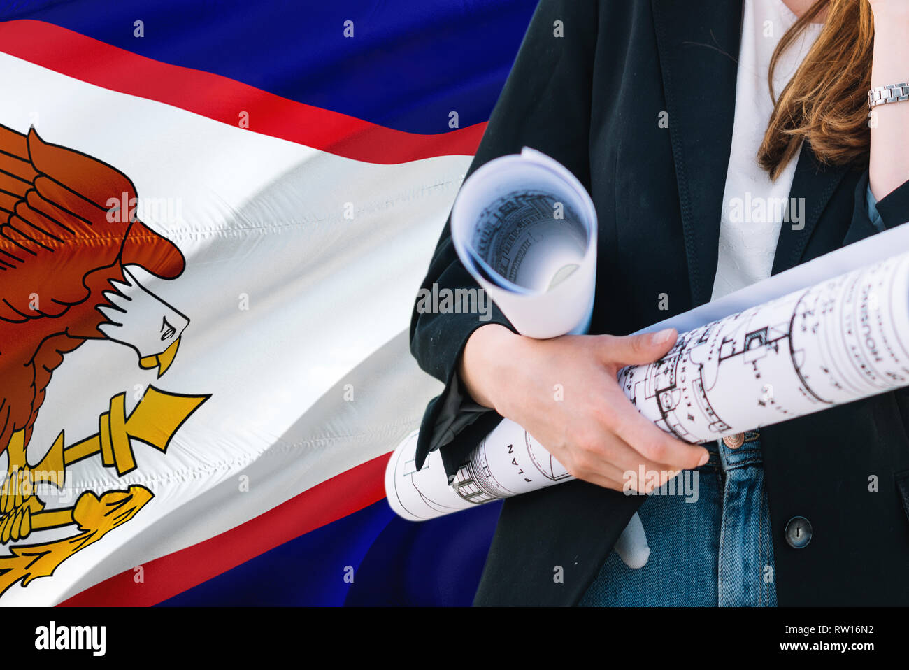 Architect woman holding blueprint against American Samoa waving flag background. Construction and architecture concept. Stock Photo