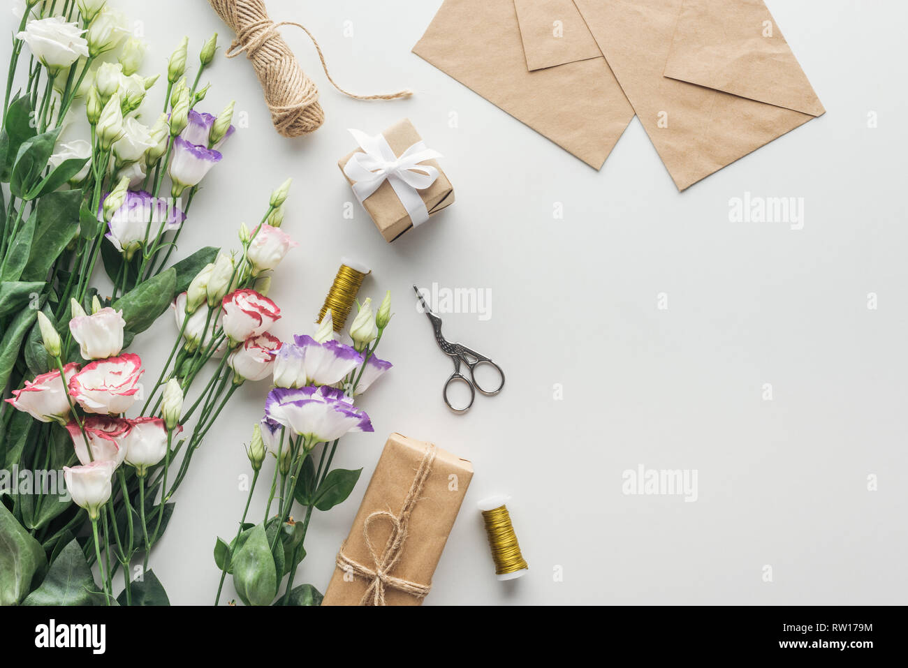 top view of eustoma, wrapped gifts, spools of thread, envelopes and ...