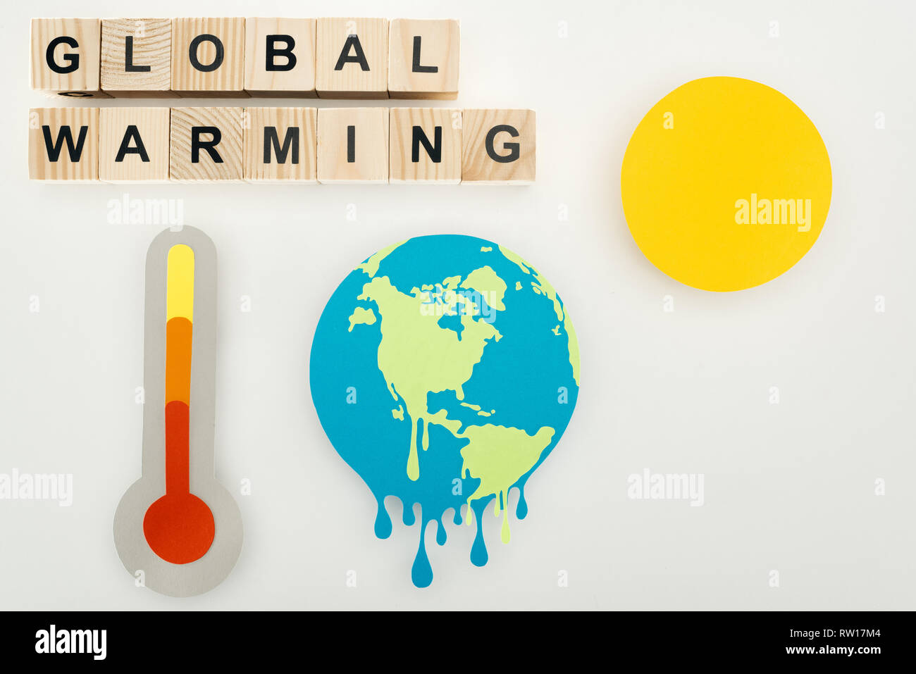 paper cut melting earth and sun, thermometer with high temperature indication on scale, and wooden cubes with "global warming" lettering on grey backg Stock Photo