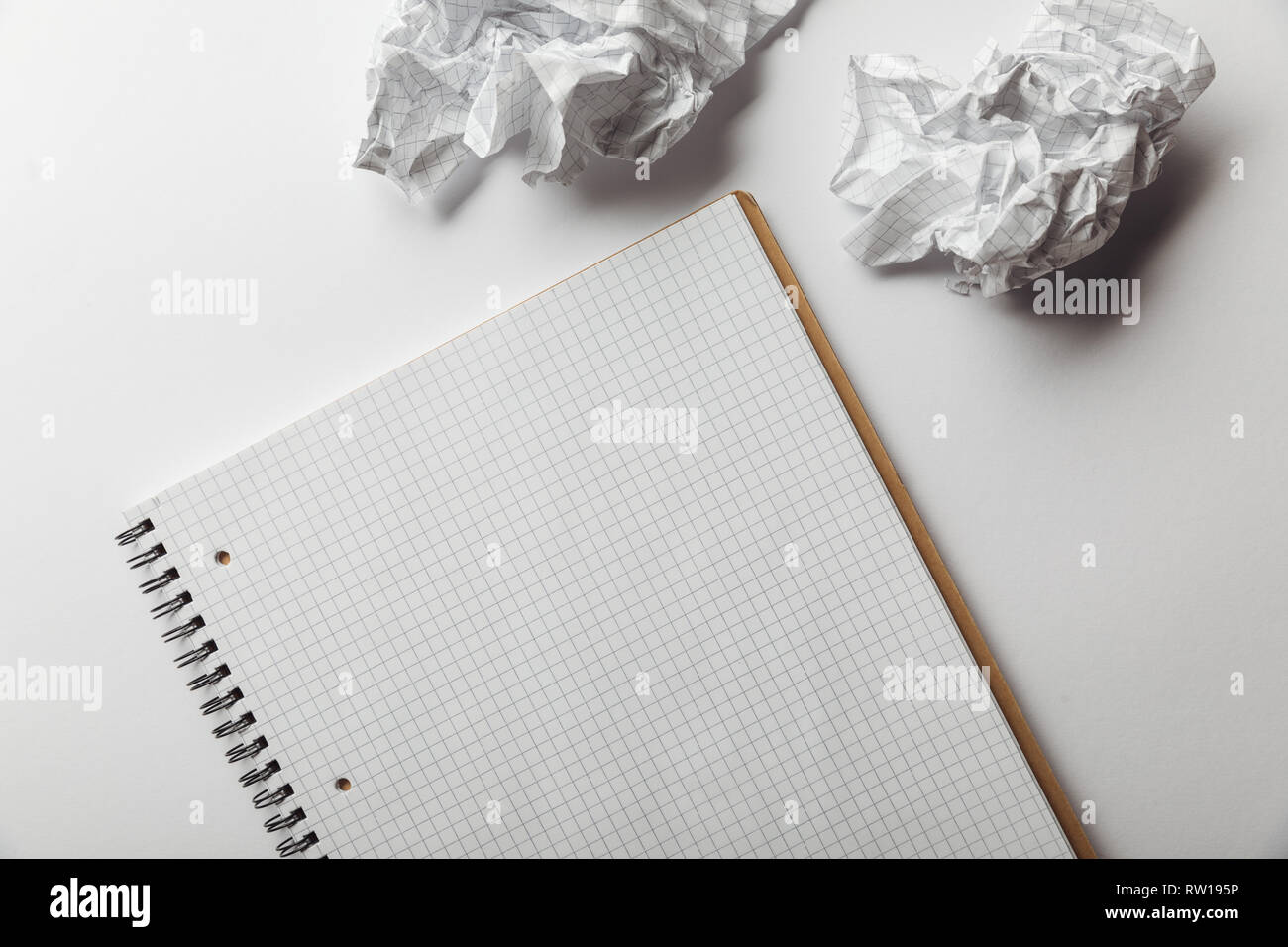 top view of notebook with blank squared page near crumpled sheets on white background Stock Photo