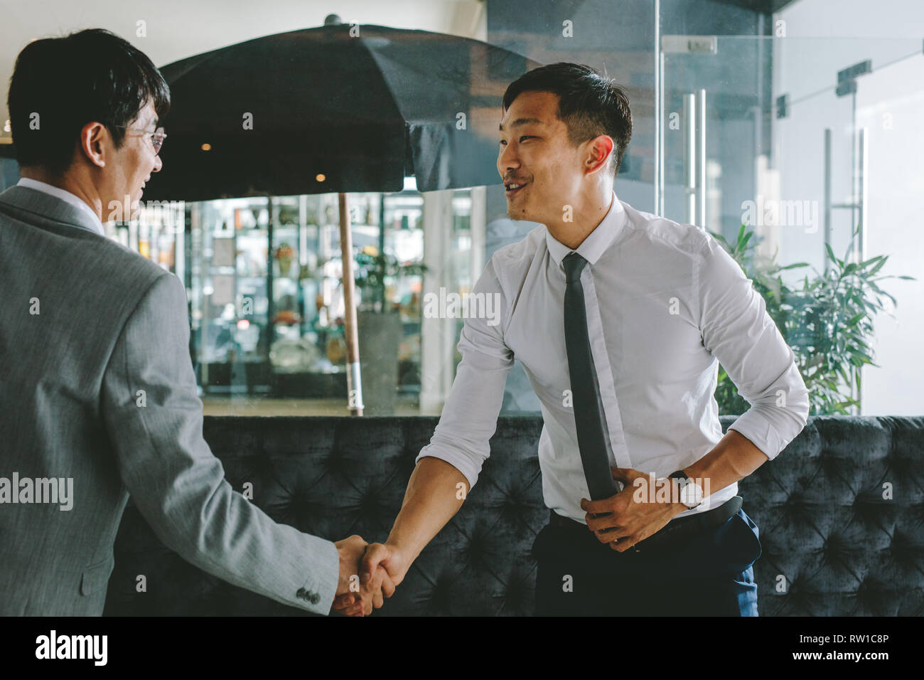 Asian business executive meeting a client at a coffee shop. Korean business people greeting each other with a handshake. Stock Photo
