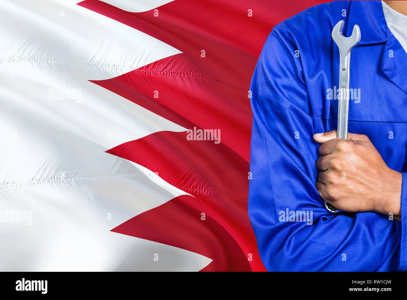 Bahraini Mechanic in blue uniform is holding wrench against waving