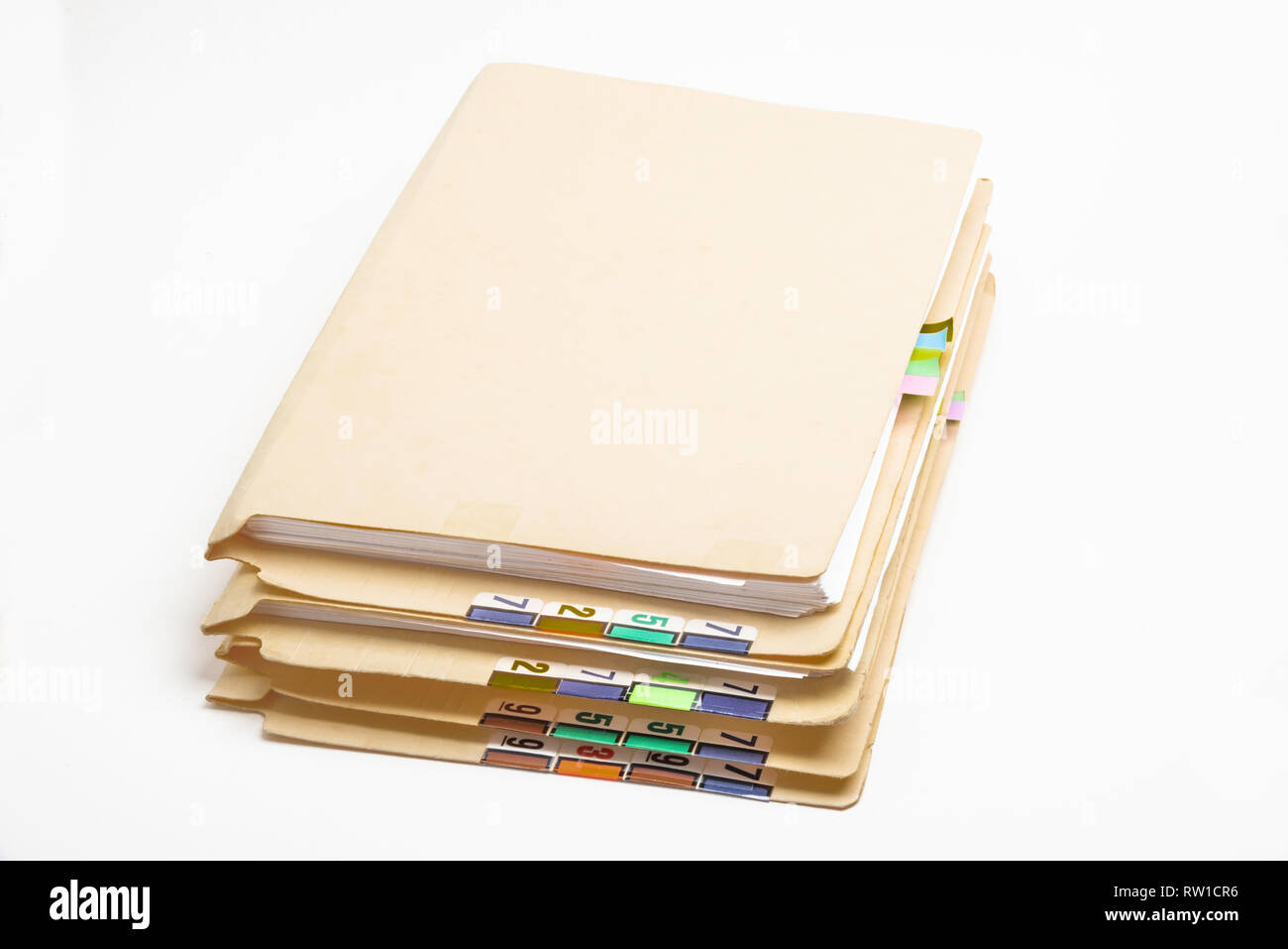 A stack of patient medical records in folders with color-coded and numbered tabs. Stock Photo