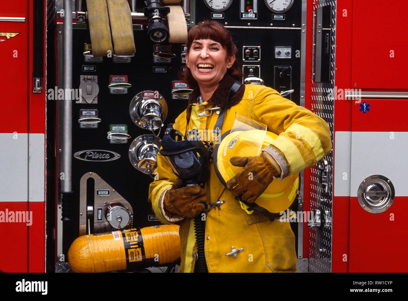 Female Hispanic Firefighter Poses in front of a Fire Truck, California, USA Stock Photo