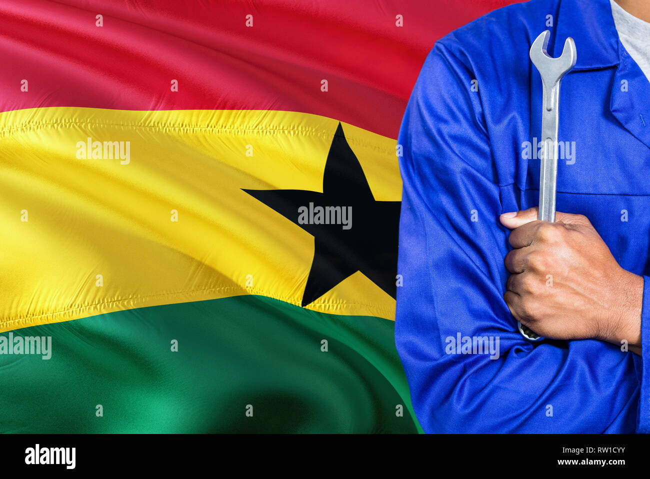Ghanaian Mechanic in blue uniform is holding wrench against waving