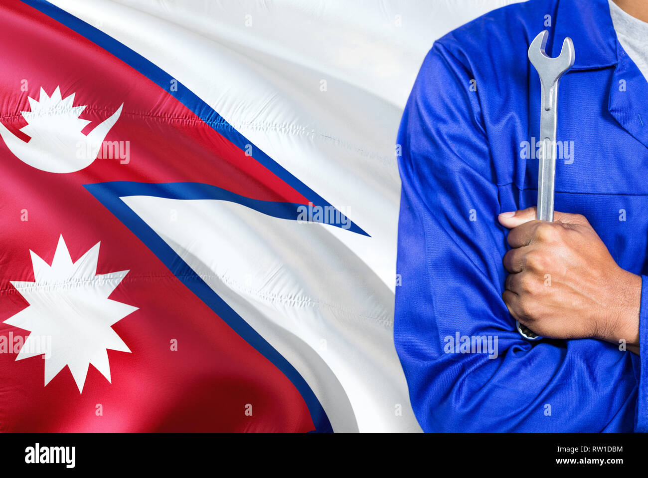 Nepalese Mechanic in blue uniform is holding wrench against waving