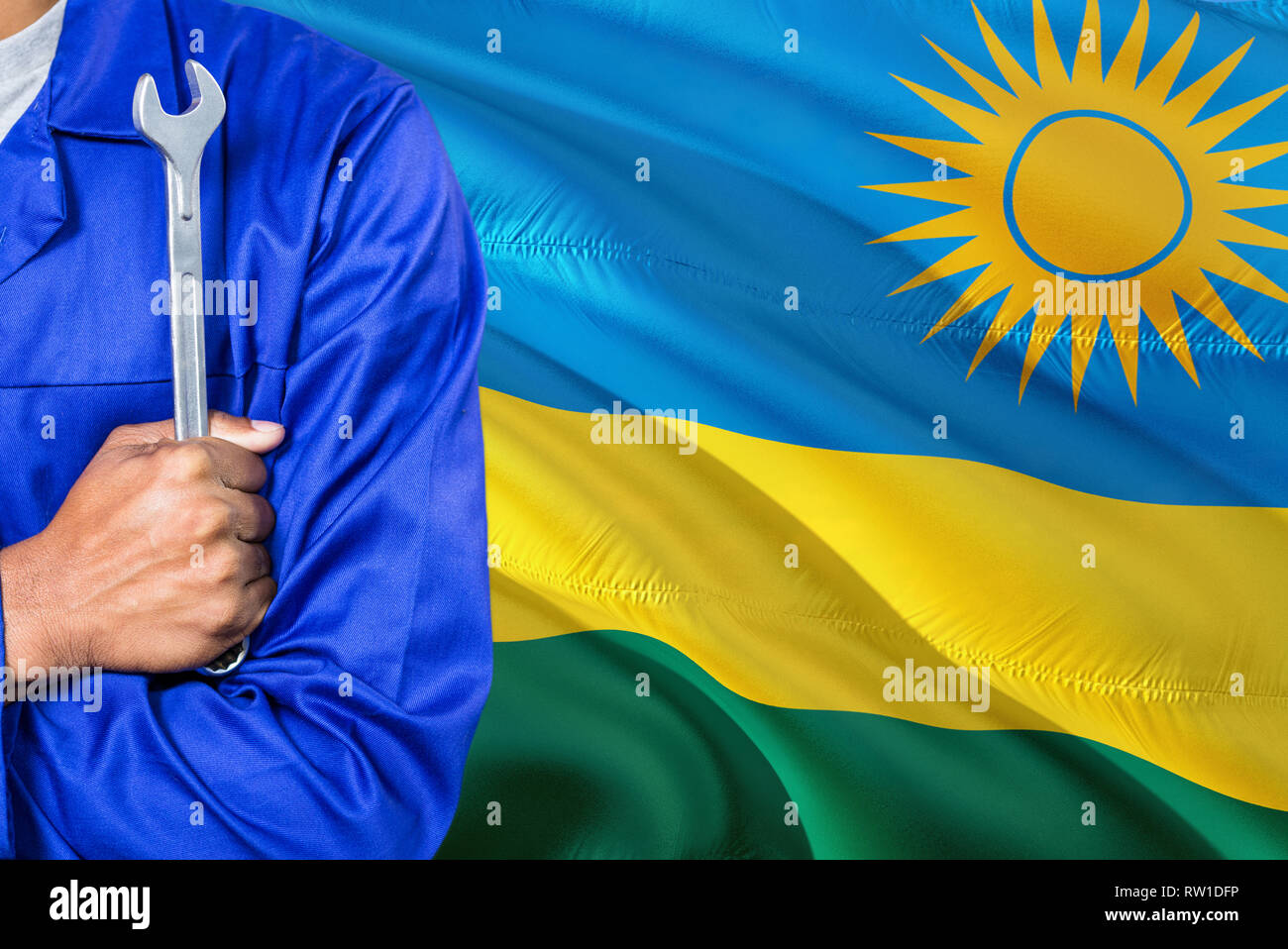Rwandan Mechanic in blue uniform is holding wrench against waving ...
