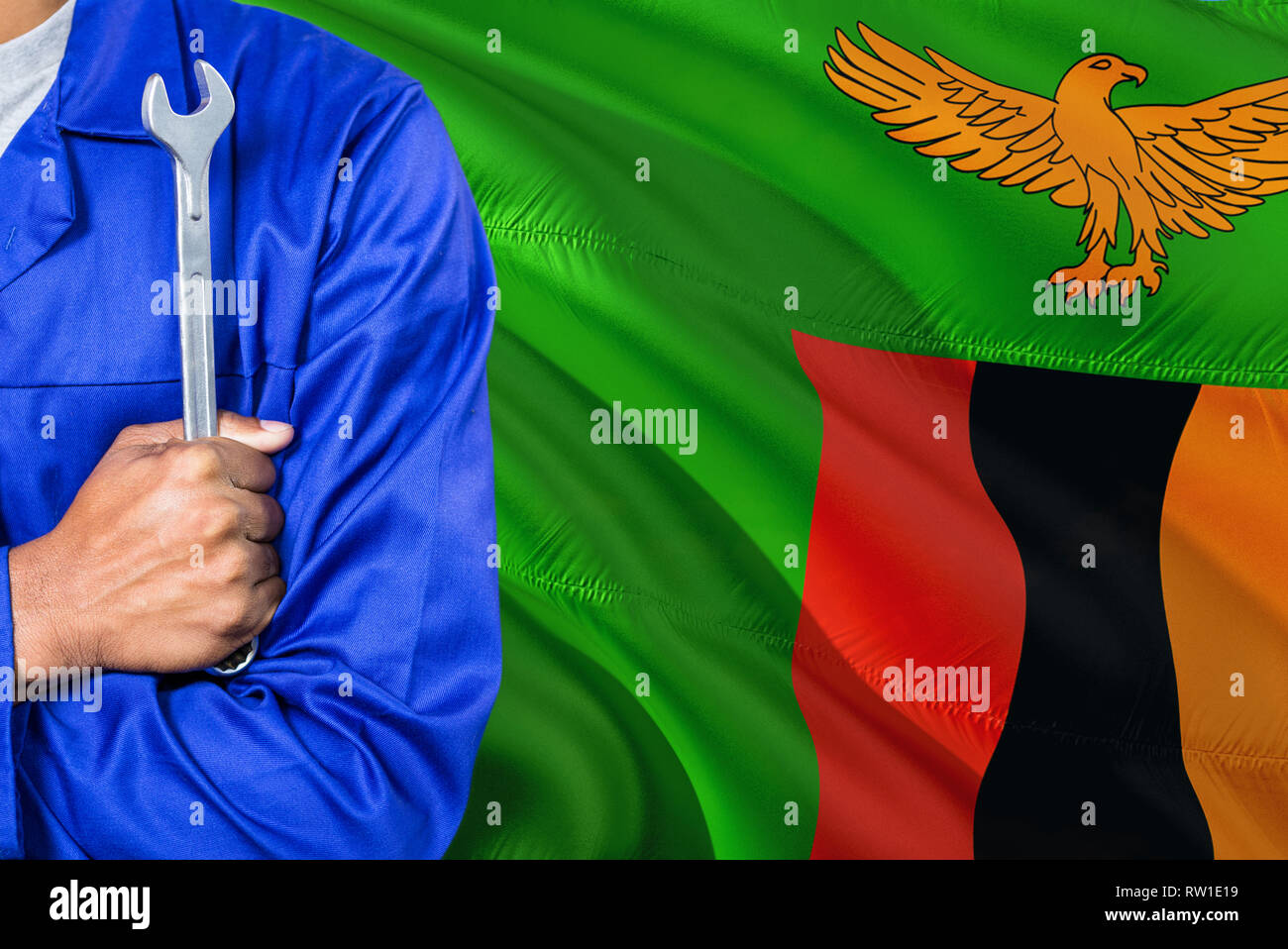 Zambian Mechanic in blue uniform is holding wrench against waving