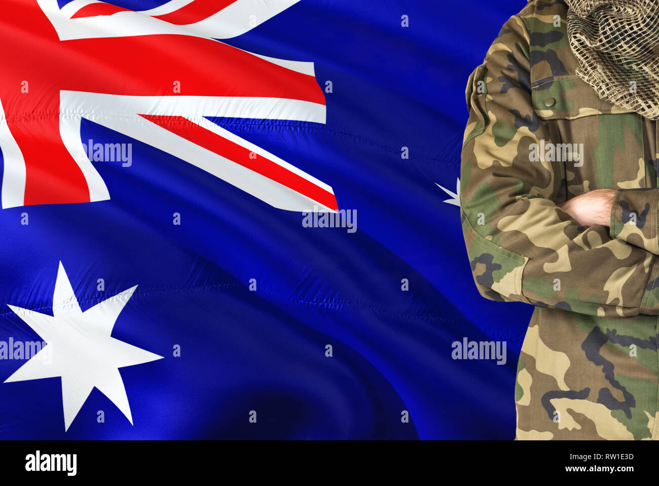 Crossed arms Australian soldier with national waving flag on background - Australia Military theme. Stock Photo