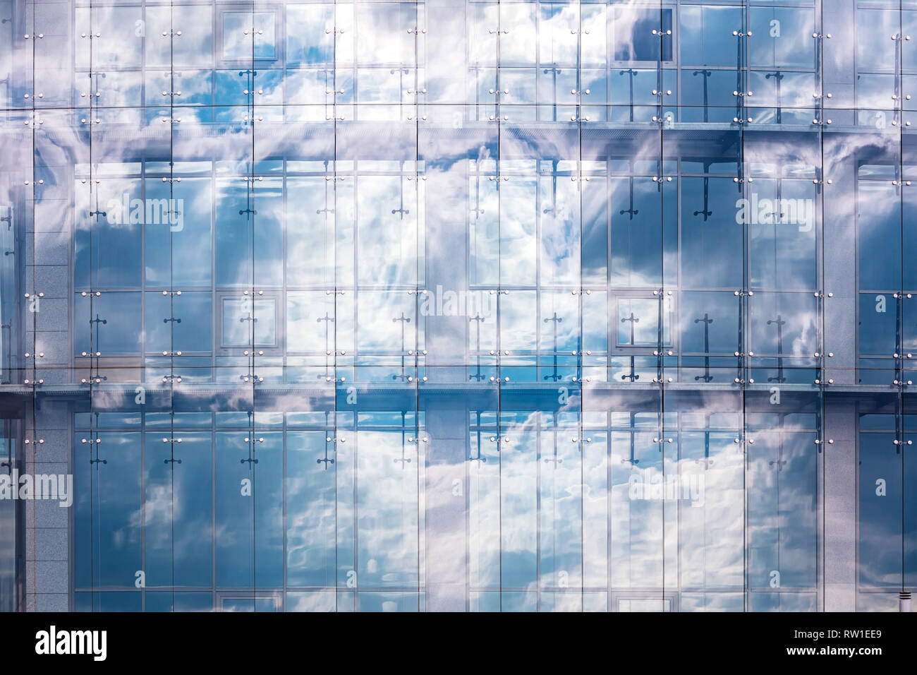 blue glass wall of office building with sky and clouds reflection. abstract glass building background Stock Photo
