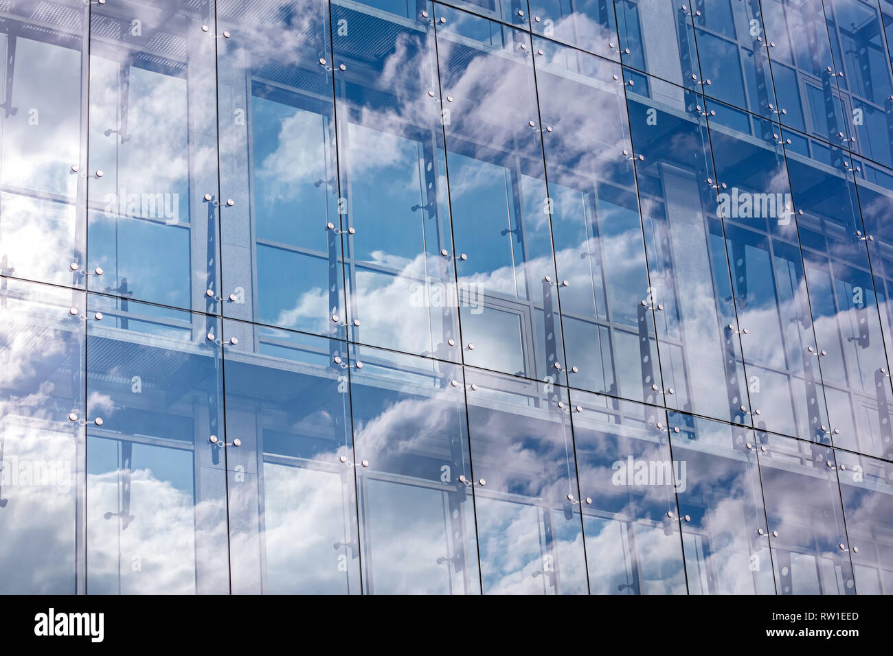 transparent glass wall of modern office building with cloudy sky reflection Stock Photo