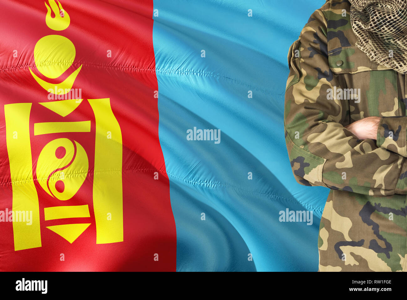 Crossed arms Mongolian soldier with national waving flag on background - Mongolia Military theme. Stock Photo
