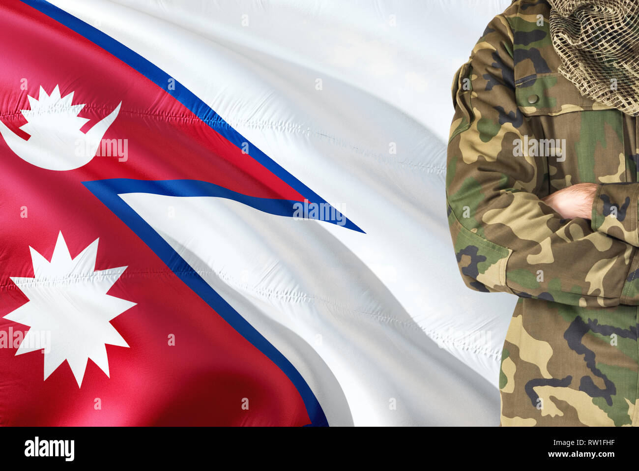 Crossed arms Nepalese soldier with national waving flag on background