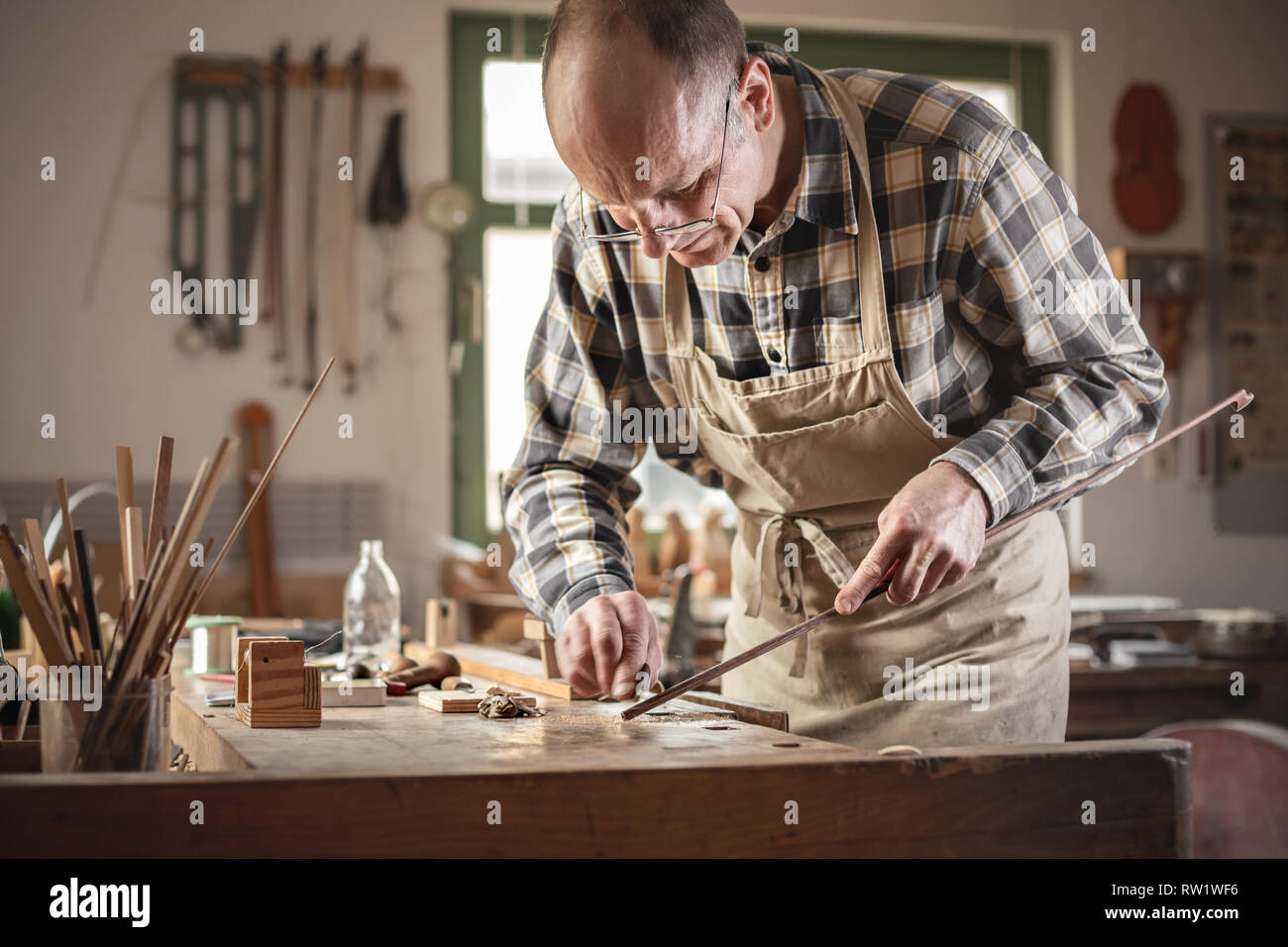 Mature artisan working on a violin bow in a workshop Stock Photo