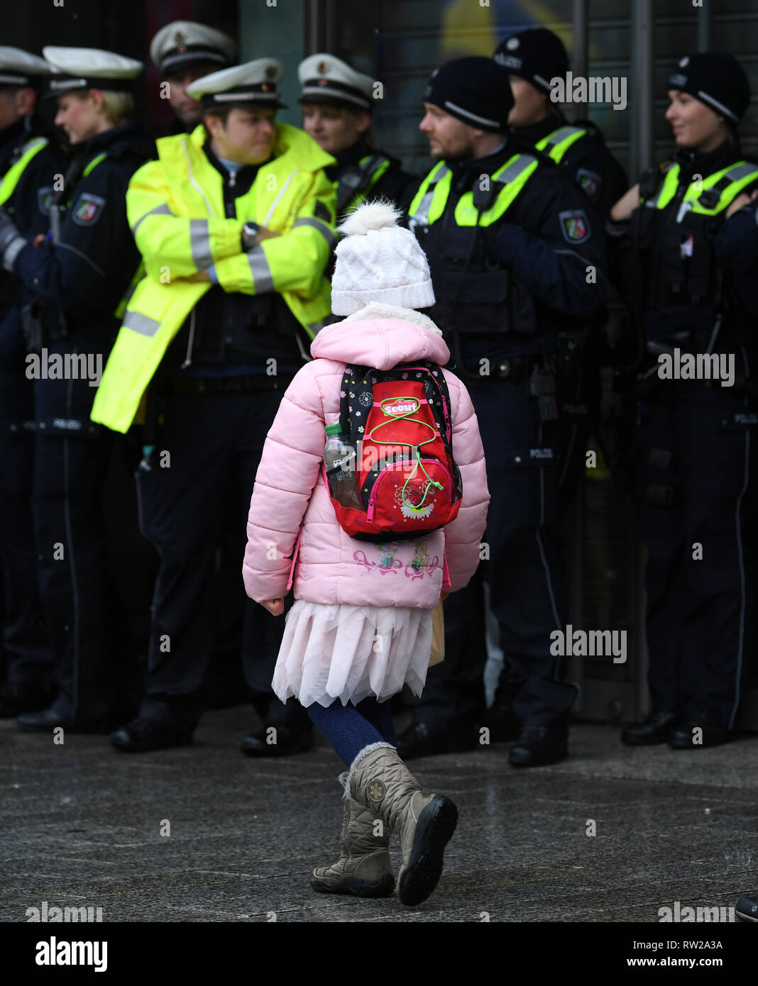 04 March 2019, North Rhine-Westphalia, Düsseldorf: A disguised girl walks past policemen during the Shrove Monday procession. With the Rose Monday processions, the Rhineland street carnival reaches its climax. Photo: Ina Fassbender/dpa Stock Photo