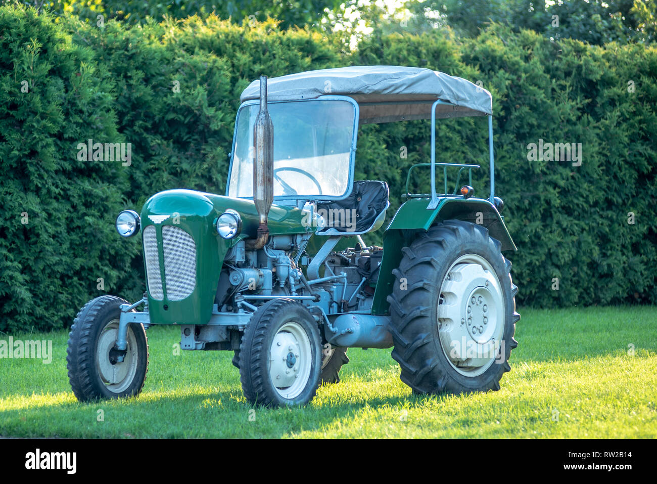 A green Polish manufactured tractor parked on the grass with green bushes behind. Broniewo, Kuyavian-Pomeranian Voivodeship, Poland Stock Photo
