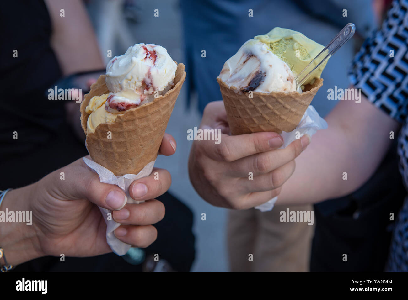 Close shot of two people enjoying several different flavors of ice cream (lody) in waffle cones. Warsaw, Masovian Voivodeship, Poland Stock Photo