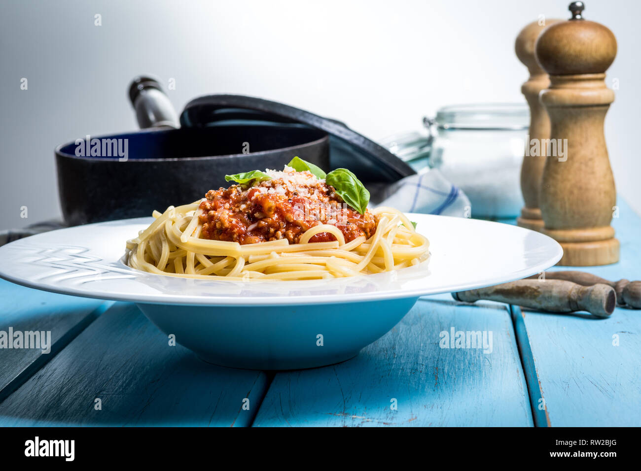 Traditional italian pasta spaghetti bolognese with minced meat, tomato, cheese parmesan and basil on blue wood table Stock Photo
