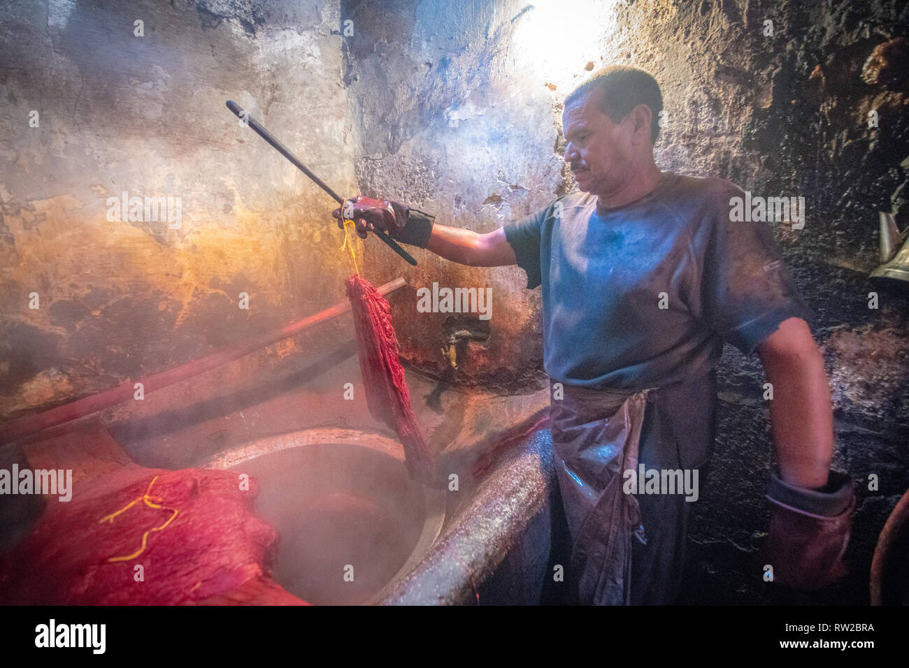 Man pulls out textile from fabric dyeing solution, Marrekech, Morocco Stock Photo