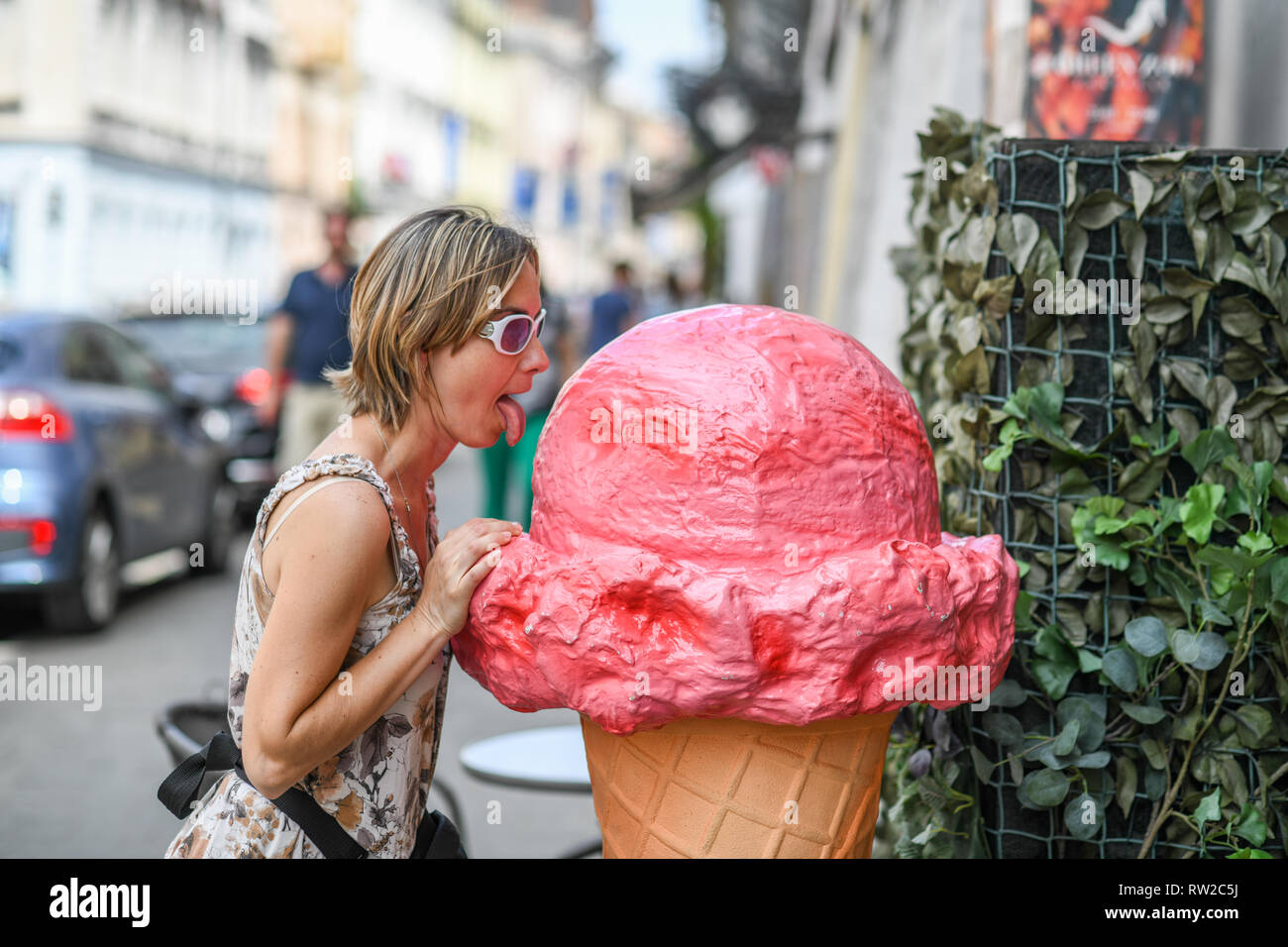 Woman humorously pretends to lick large plastic ice-cream cone, Krak—w, Lesser Poland Voivodeship, Poland. Stock Photo