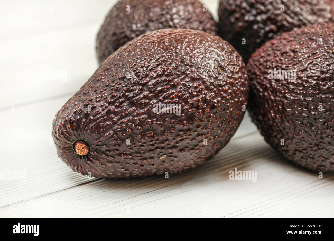 Dark brown ripe avocados on white boards. Close up, detail on skin