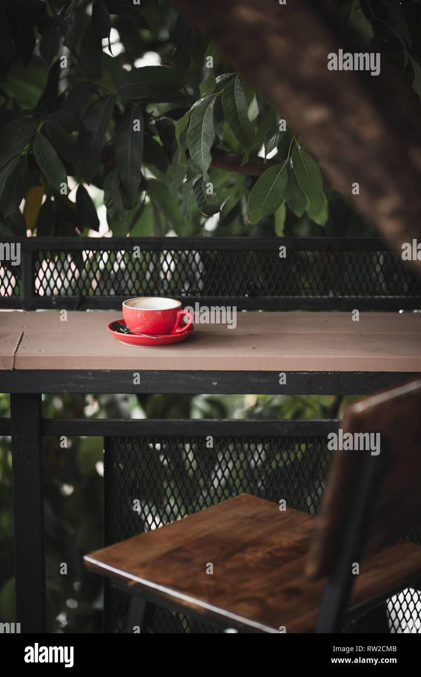 Abstract emotional scene of hot coffe in red coffee cup on table at cafe in morning time. Weekend activity and relaxation. favorite beverage concept o Stock Photo