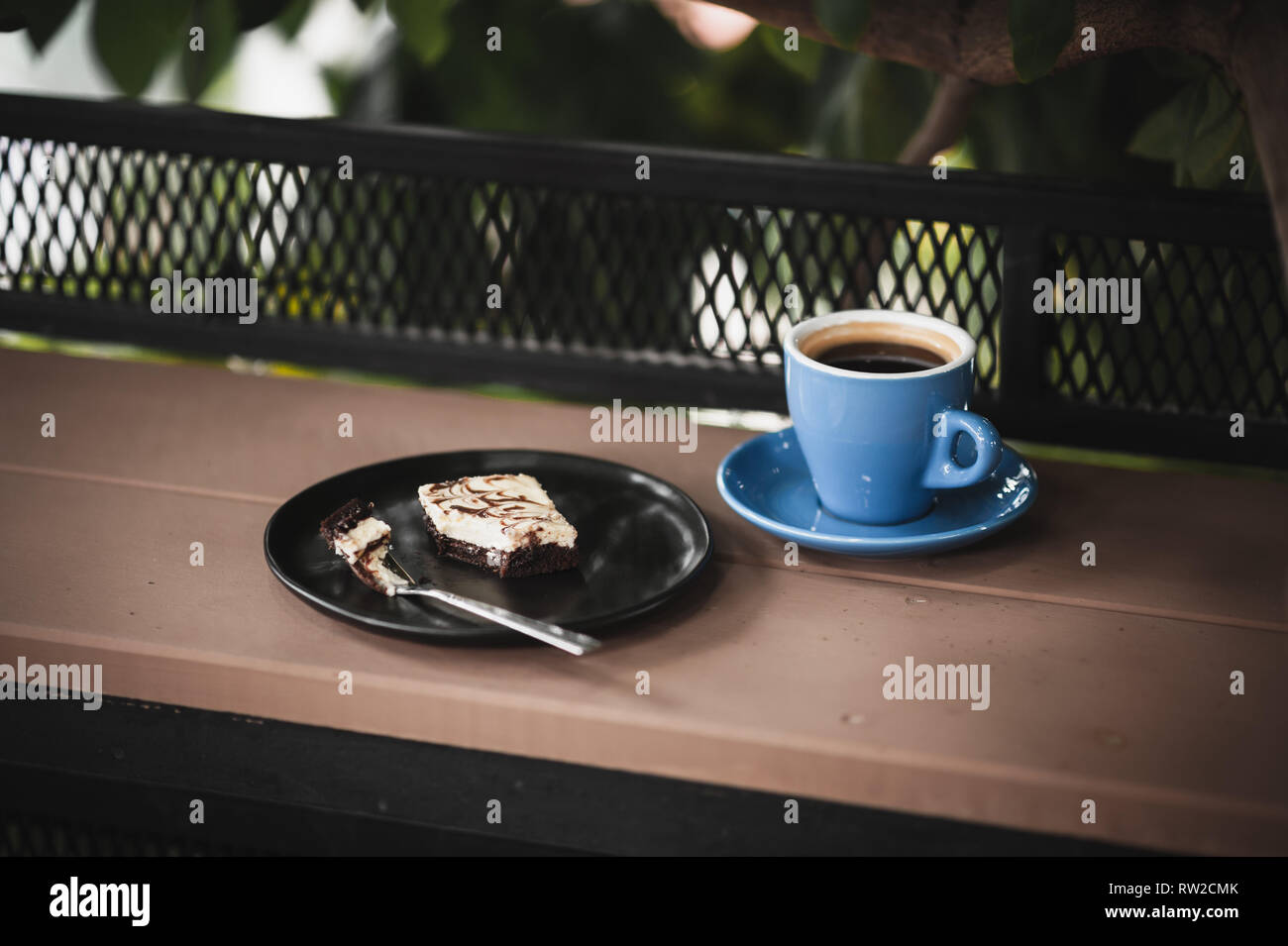 Abstract scene of coffee break meal set including black coffee, and brownie cheese cake on outdoor wood bar. Weekend morning activity with good emotio Stock Photo