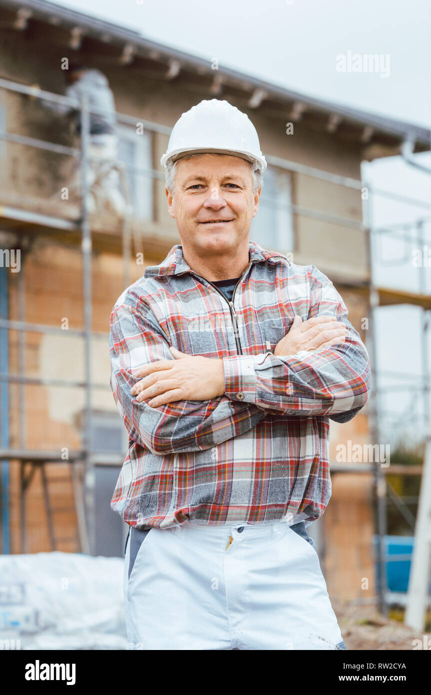 Proud plasterer standing in front of scaffold on construction site Stock Photo