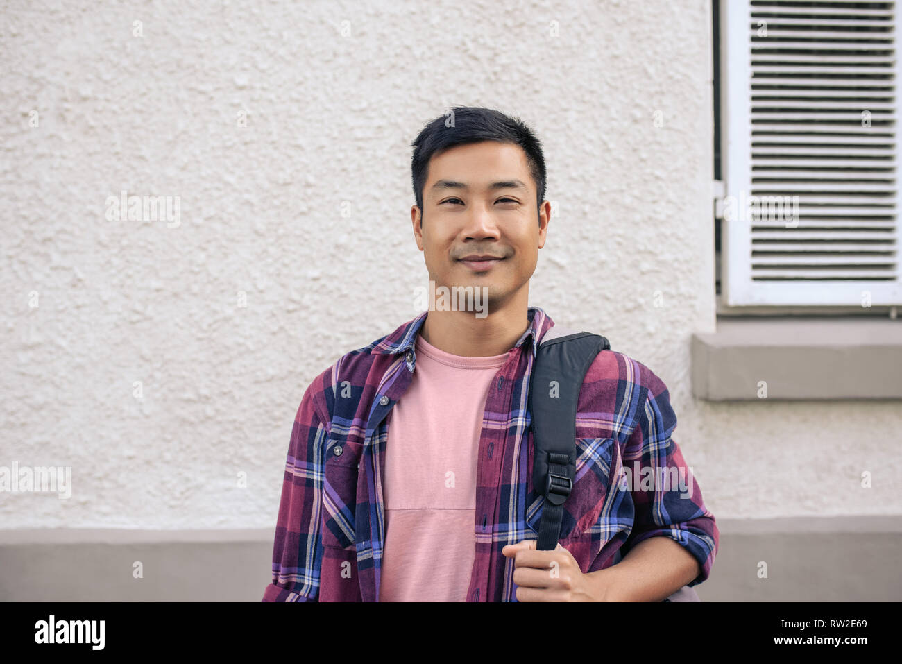 Young Asian man standing outside in the city and smiling Stock Photo
